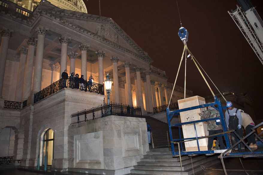 Riggers load a crate containing the bronze statue of Rosa Parks onto a basket suspended from a crane as it is delivered to the U.S. Capitol's Memorial Door, in Washington, Friday, Feb. 22, 2013, where it will join the U.S. Capitol Art Collection. Authorized by Public Law 109-116, as modified by Public Law 110-120, the Rosa Parks statue represents the first commission of a full-sized statue approved and funded by the U.S. Congress since 1873. It will be installed in National Statuary Hall in the United States Capitol on Feb. 27, 2013. (AP Photo/Cliff Owen)