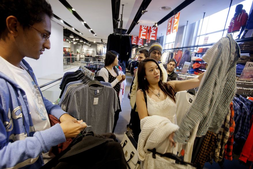 ** FILE ** In this Wednesday, Dec. 12, 2012, photo, Lana Nguyen, right, holds up a shirt while helping friend Chris Ghiathi, left, shop in an H&M store, in Atlanta. (AP Photo/David Goldman)