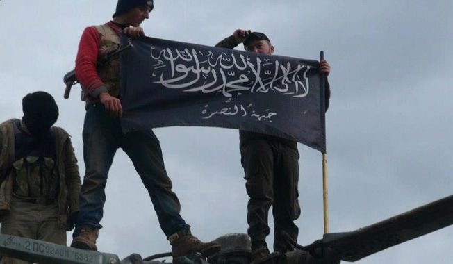 **FILE** Rebels from al Qaeda-affiliated Jabhat al-Nusra wave their brigade flag on Jan. 11, 2013, as they step on the top of a Syrian air force helicopter at a Taftanaz air base in Idlib province in northern Syria that was captured by the rebels. (Associated Press/Edlib News Network)
