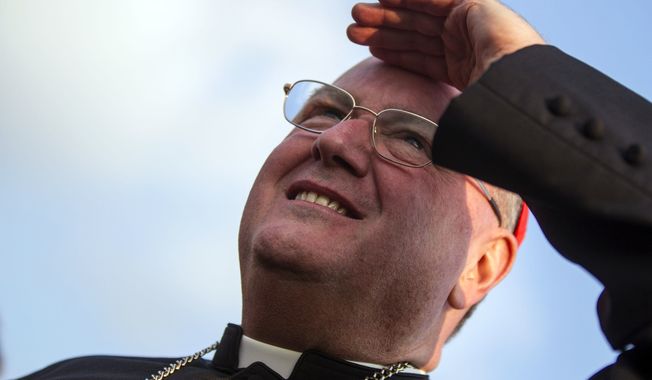 ** FILE ** Cardinal Timothy Dolan, archbishop of New York, shades his eyes as he looks at the helicopter taking Pope Benedict XVI to Castel Gandolfo, in Rome on Thursday, Feb. 28, 2013. (AP Photo/Angelo Carconi)

