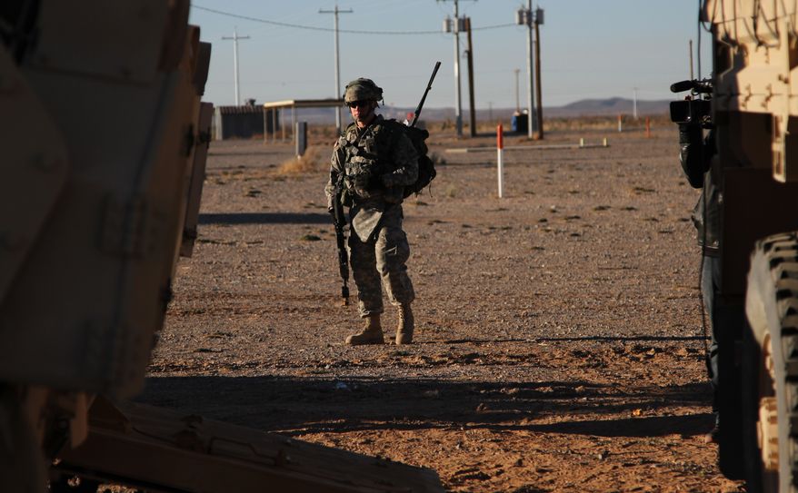 A soldier stands near a tank and a truck before a training exercise in Fort Bliss, Texas, on Wednesday, Jan. 23, 2013. The Army is rolling out a new training platform that allows the integration of live units, simulators and computer-generated forces. It is expected to allow cheaper, more frequent training. (AP Photo/Juan Carlos Llorca)