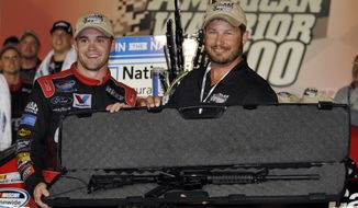 **FILE** Ricky Stenhouse Jr., left, poses with the rifle he won with retired U.S. Special Forces soldier Greg Stube in victory lane after winning the NASCAR Nationwide Series auto race at Atlanta Motor Speedway, Saturday, Sept. 1, 2012, in Hampton, Ga. (AP Photo/Rainier Ehrhardt)