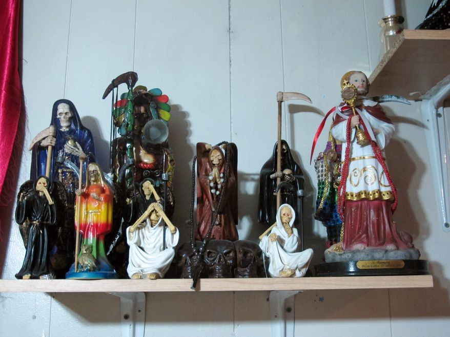 ** FILE ** In this Feb. 12, 2013, photo, statues of La Sante Muerte from an altar run by Arely Vazquez Gonzalez, a Mexican immigrant and transgender woman, is shown inside a Queens, NY apartment. La Santa Muerte, an underworld saint most recently associated with the violent drug trade in Mexico, now is spreading throughout the U.S. among a new group of followers ranging from immigrant small business owners to artists and gay activists. (AP Photo/Russell Contreras)