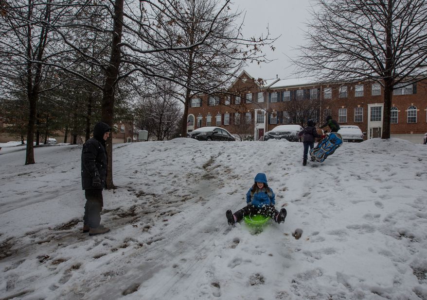 Children sled down a small hill while their parents watch in a neighborhood in Fairfax, Va., on March 6, 2013. (Andrew S. Geraci/The Washington Times)
