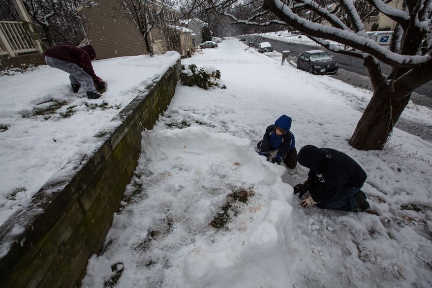 Mason Moy (left), 14, Calvin Crist (center), 13, and Sam Gustason, 13, build a snow fort in a front yard during a snow day in Fairfax, Va., on March 6, 2013. (Andrew S. Geraci/The Washington Times)