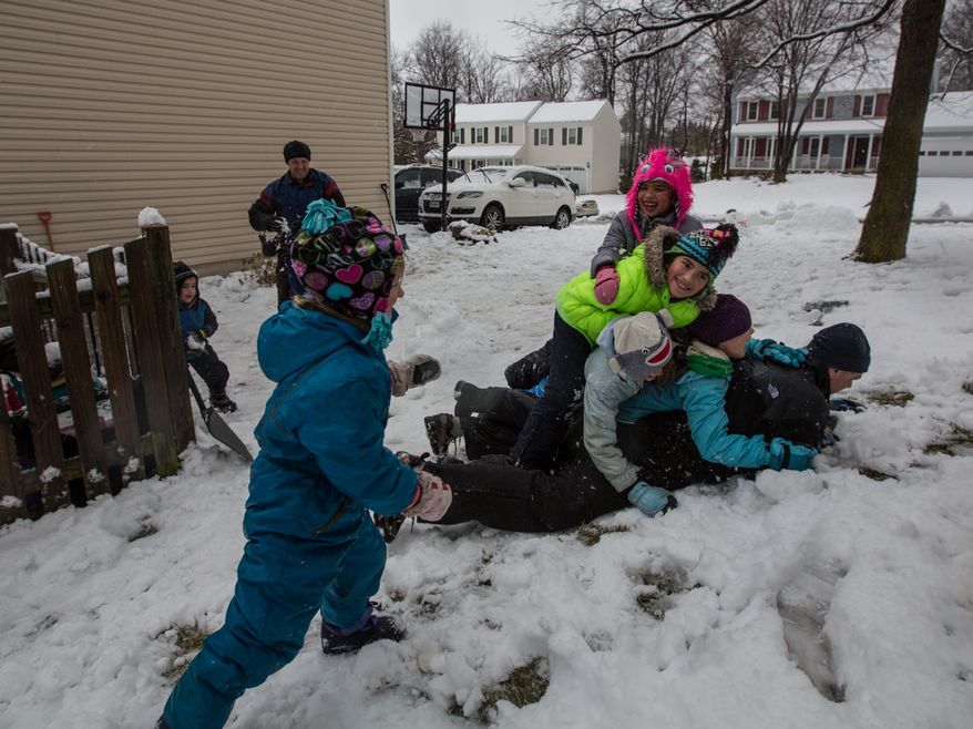 Members of the Sweeney and Powers families pile on top of Patrick Sweeney during a snowball fight in Fairfax, Va., on March 6, 2013. (Andrew S. Geraci/The Washington Times)