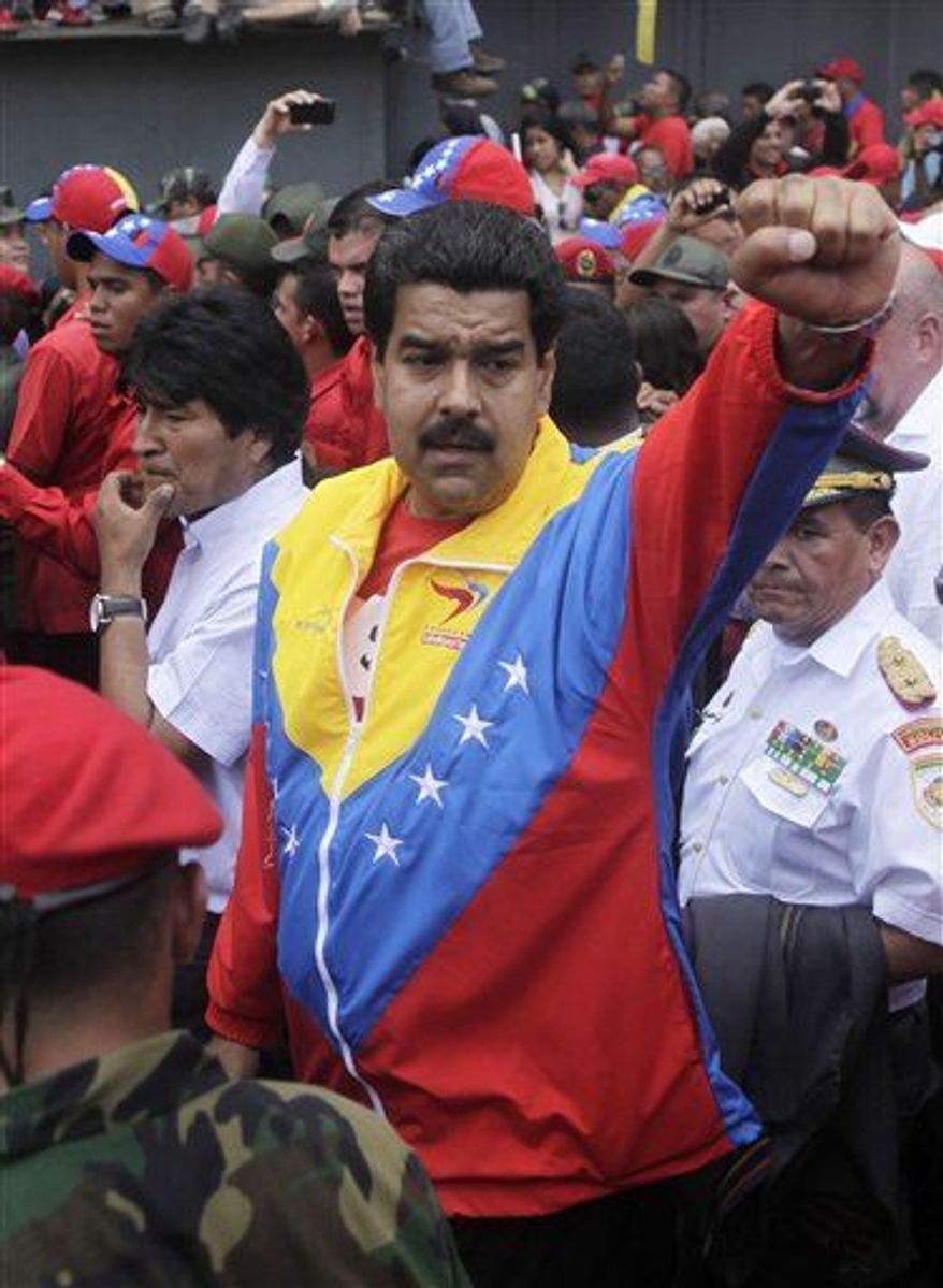 Venezuela's Vice President Nicolas Maduro, center, raises his fist next to Bolivia's President Evo Morales, center left, as they walk along the coffin containing the remains of President Hugo Chavez in Caracas, Venezuela, Wednesday, March 6, 2013.