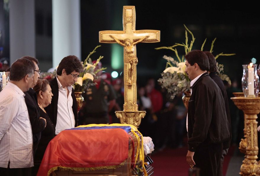 In this photo released by Miraflores Press Office, Hugo Chavez' mother Elena Frias, third from left, and brothers Adan, second from left, Argenis, first right, and Adelis, fourth from right, stand next to the flag-draped coffin containing the body of Venezuela's late President Hugo Chavez on display during his wake at a military academy where his body will lie in state until his funeral in in state in Caracas, Venezuela, Wednesday, March 6, 2013. (AP Photo/Miraflores Presidential Press Office)