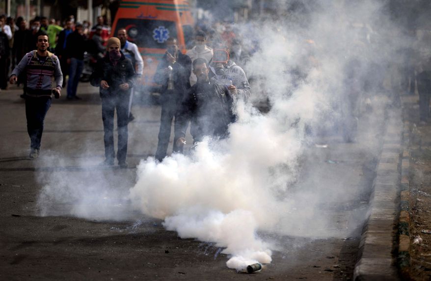 Egyptian protesters react from a tear gas canister fired by riot police, not pictured, during clashes near a state security building in Port Said, Egypt, Thursday, March 7, 2013. Clashes between protesters and police continued into a fifth day on Thursday in the restive Egyptian city of Port Said. (AP Photo/Khalil Hamra)