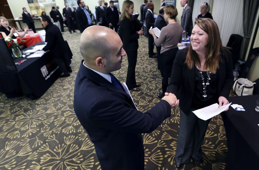 Sayed Mouawad (left) of Providence, R.I., shakes hands with Jillian Wallace of Matix Inc. during a job fair in Boston on Monday, Feb. 25, 2013. (AP Photo/Michael Dwyer)