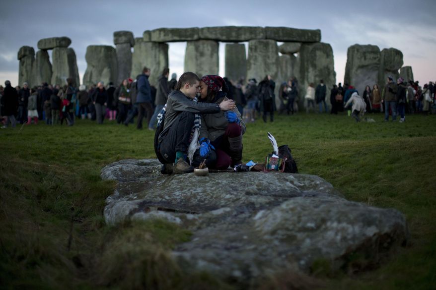 People embrace by the ancient stone circle of Stonehenge, in southern England on the annual Winter Solstice, in this Friday, Dec. 21, 2012, file photo. (AP Photo/Matt Dunham, File)