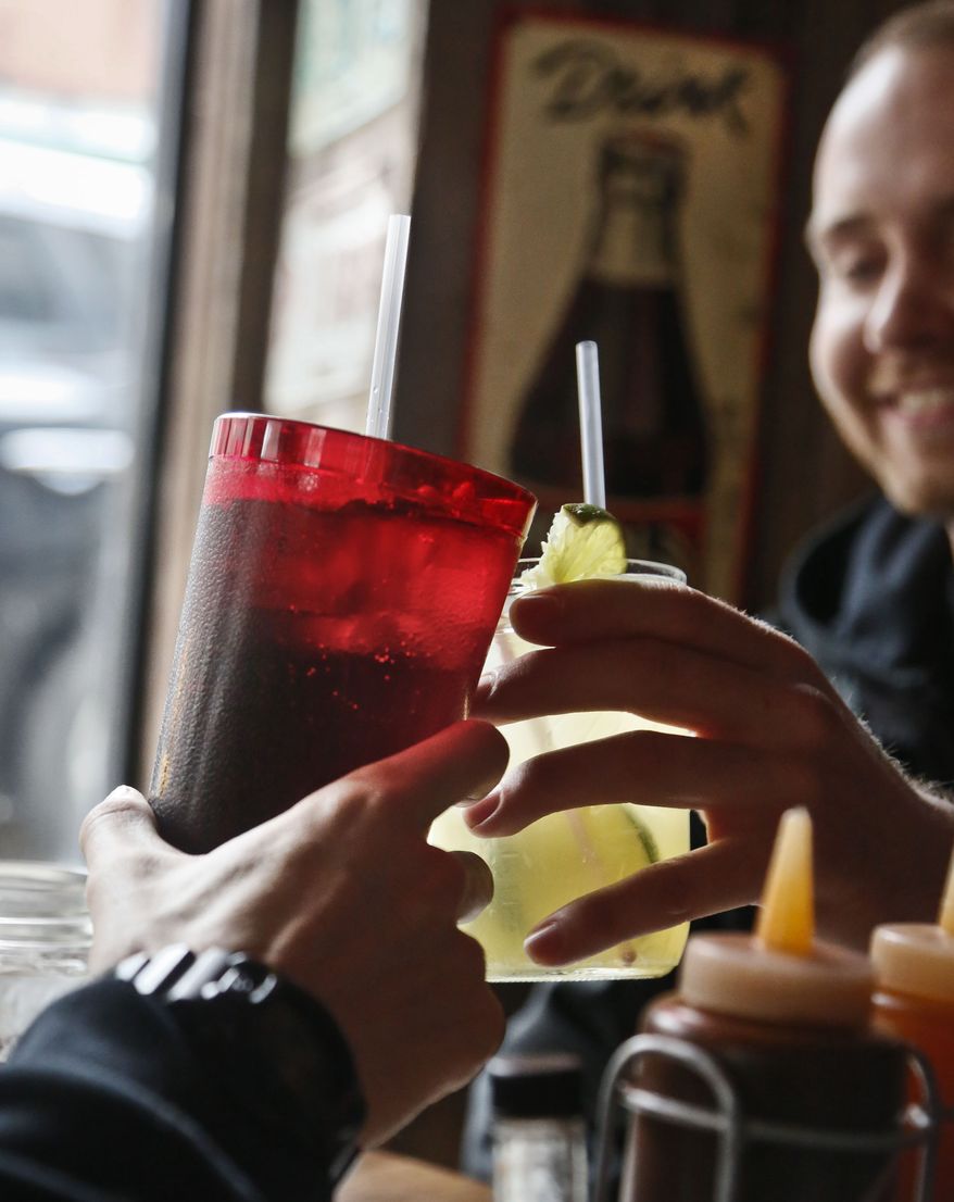 **FILE** Customers at Brother Jimmy's BBQ in New York call cheers with 24-ounce (left) and 16-ounce beverages on March 8, 2013. (Associated Press)