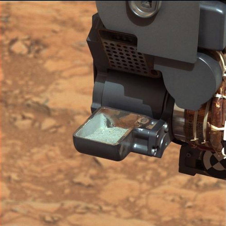 The Mars rover Curiosity holds a scoop of powdered rock. The rover recently drilled into a Martian rock for the first time and transferred a pinch of powder to its instruments to analyze the chemical makeup. (AP Photo/NASA)