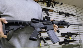 John Jackson, co-owner of Capitol City Arms Supply, shows an AR-15 assault rifle for sale at his business in Springfield, Ill., on  Jan. 16, 2013. (Associated Press) **FILE** 