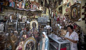 Maria Villena looks at inventory at a store that sells Catholic iconography in Lima, Peru, Wednesday, March 13, 2013. (AP Photo/Martin Mejia)
