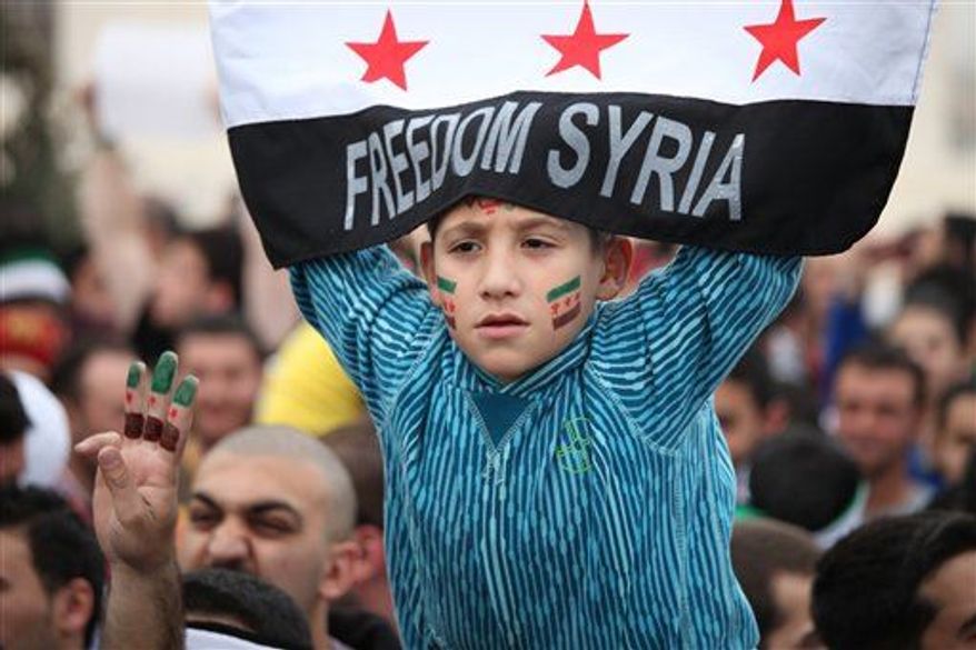 A Syrian boy waves the Syrian revolutionary flag during a celebration to commemorate the second anniversary of the Syrian revolution, in Amman, Jordan, Friday, March, 15, 2013. Around a thousand Syrians gathered in front of the Syrian embassy, and chanted slogans against Assad, and the Baath regime that has ruled Syria for the last 40 years. (AP Photo/Mohammad Hannon)