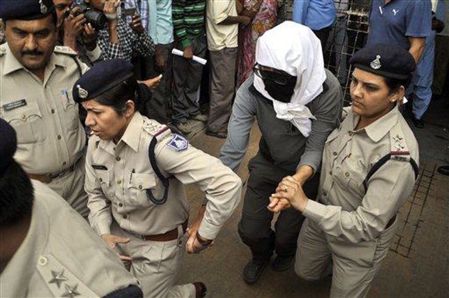 A Swiss woman, center, who was gang raped by a group of eight men while touring by bicycle with her husband, is escorted by policewomen for a medical examination at a hospital in Gwalior, in the central Indian state of Madhya Pradesh, Saturday, March 16, 2013. Thirteen men were detained and questioned in connection with the attack. (Associated Press)