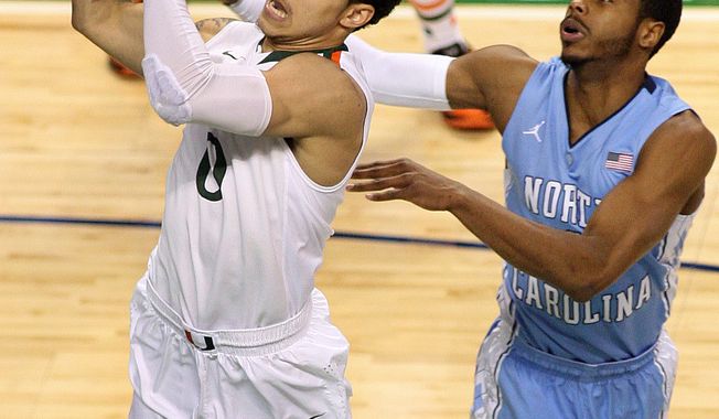 Miami&#x27;s Shane Larkin makes a shot in front of North Carolina State&#x27;s Dexter Strickland in the first half of an NCAA basketball game during the championship game of the ACC Tournament in Greensboro, N.C. on Sunday March 17, 2013. (AP Photo/Burlington Times-News, Al Drago)