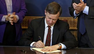 ** FILE ** Colorado Gov. John Hickenlooper is applauded by lawmakers as he signs the state&#39;s gun-control bill into law at the Capitol in Denver on Wednesday, March 20, 2013. (AP Photo/Ed Andrieski, Pool)