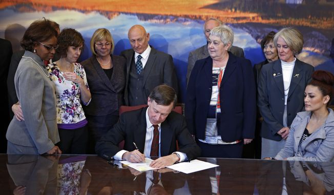 ** FILE ** Sponsors and family members of victims watch as Colorado Gov. John Hickenlooper signs gun-control bills into law at the Capitol in Denver on Wednesday, March 20, 2013. The bills, which place new restrictions on firearms, thrust Colorado into the national spotlight as a potential test of how far the country might be willing to go on new restrictions after the horror of the Newtown, Conn., and Aurora, Colo., shootings. (Associated Press)