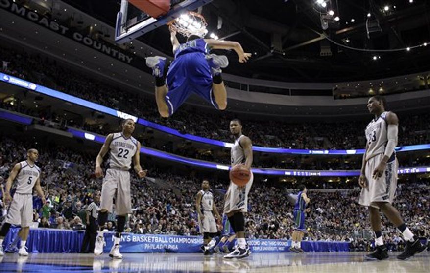 Florida Gulf Coast's Chase Fieler (20) hangs from the rim after a dunk as Georgetown's Markel Starks (5), Otto Porter Jr. (22), D'Vauntes Smith-Rivera (4), Mikael Hopkins (3) and Aaron Bowen (23) look on during the second half of a second-round game of the NCAA college basketball tournament on Friday, March 22, 2013, in Philadelphia. Florida Gulf Coast won 78-68. (AP Photo/Matt Rourke)