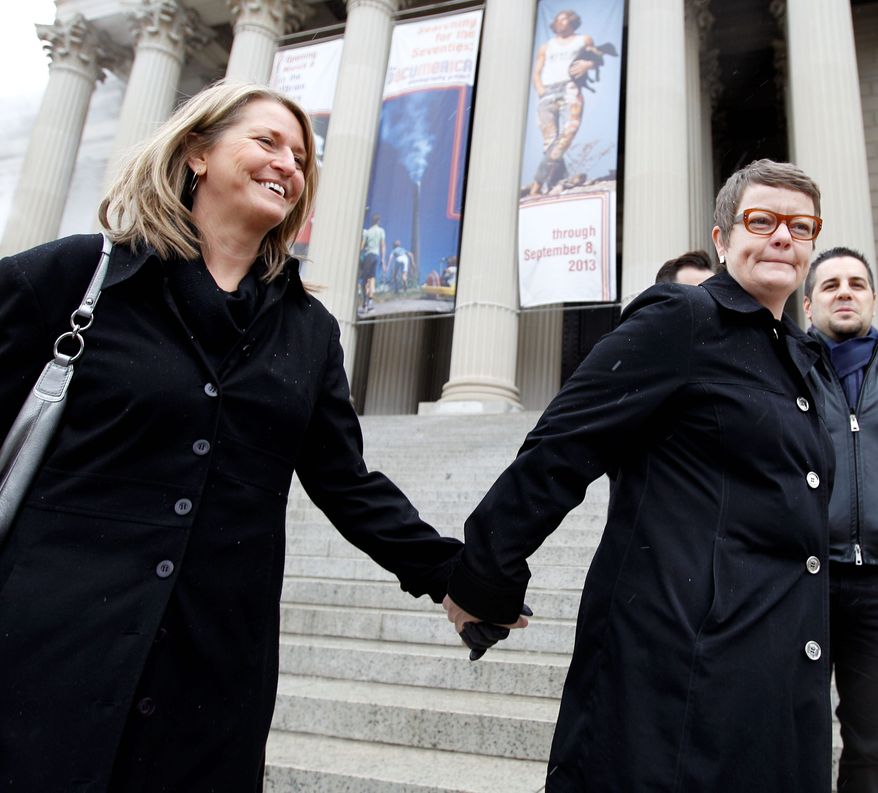 Sandy Stier (left) and Kris Perry of Berkeley, Calif., hold hands Monday by the National Archives. Tens of thousands of gay-marriage advocates and opponents are expected to be in the District this week. (Associated Press)