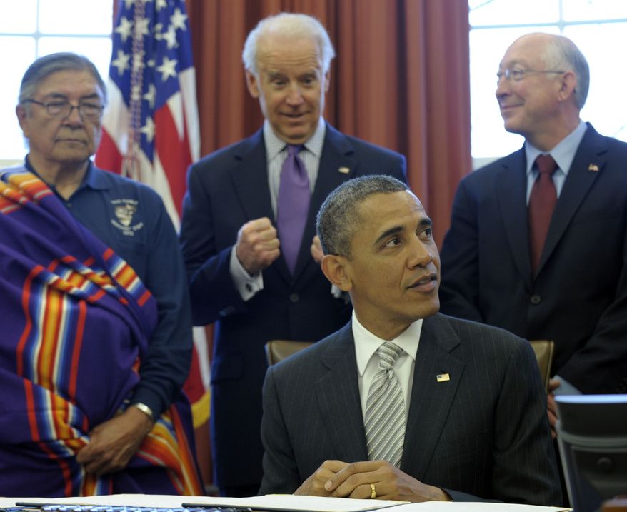 Vice President Joseph R. Biden, center, reacts after President Barack Obama signed legislation under the Antiquities Act designating five new National Monuments, Monday, March 25, 2013, in the Oval Office of the White House in Washington. From left are, Samuel Gomez, War Chief, Taos Pueblo, Biden, and Interior Secretary Ken Salazar. (AP Photo/Susan Walsh)