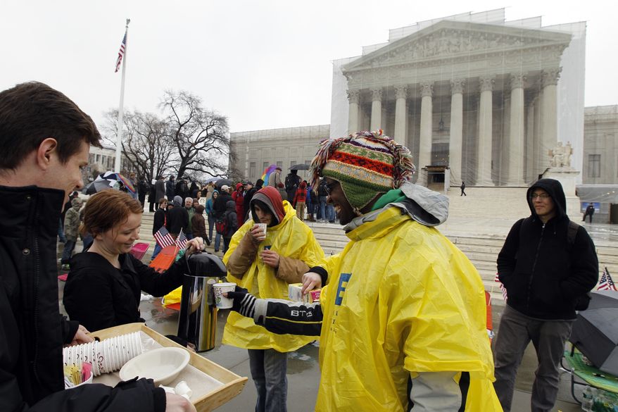 Jeff Thomson (left) and Kelsi Browning hands out free coffee to people who wait outside of the U.S. Supreme Court in Washington on March, 25, 2013, a day before the case for gay and lesbian couples rights, will be argued before the Supreme Court. (Associated Press)