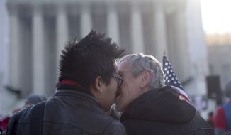 Wyatt Tan (left) and Mark Nomadiou, both of New York City, kiss in front of the Supreme Court in Washington on Wednesday, March 27, 2013, before the start of a court hearing on the 1996 Defense of Marriage Act (DOMA). In the second of back-to-back gay-marriage cases, the high court is turning to a constitutional challenge to the law that prevents legally married gay Americans from collecting federal benefits generally available to straight married couples. (AP Photo/Carolyn Kaster)