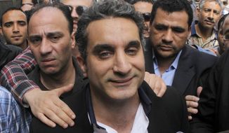 A bodyguard secures popular Egyptian television satirist Bassem Youssef, who has come to be known as Egypt&#39;s Jon Stewart, as he enters the Egyptian state prosecutor&#39;s office to face accusations of insulting Islam and the country&#39;s Islamist leader, in Cairo on Sunday, March 31, 2013. (AP Photo/Amr Nabil)