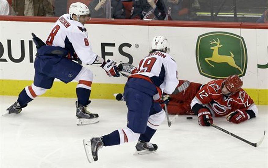 Carolina Hurricanes' Eric Staal (12) falls to the ice chasing the puck against Washington Capitals' Alex Ovechkin (8), of Russia, and Nicklas Backstrom (19), of Sweden, during the third period of an NHL hockey game in Raleigh, N.C., Tuesday, April 2, 2013. Washington won 5-3. (AP Photo/Gerry Broome)