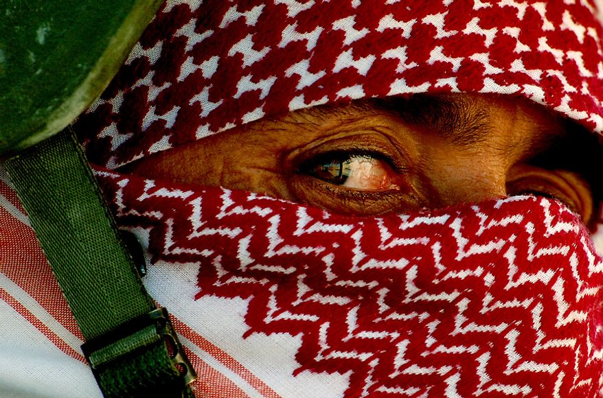 Iraqi policemen wrap their faces with scarves to conceal their identity before heading out on patrols from Al Huriya Police Station in Ramadi, Iraq, July 27, 2006. (U.S. Air Force photo by Tech. Sgt. Jeremy T. Lock)