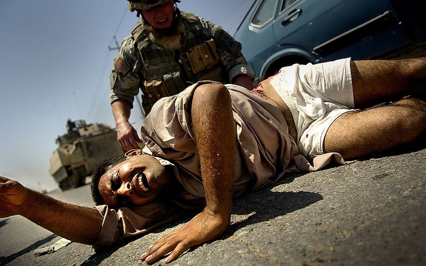 August 16, 2006: CPL David Stigers from Bravo Company, 2nd Battalion, 6th Infantry Regiment, 1st Armored Division, Baumholder, GE, administers first aid to an injured Iraqi man that was shot. U.S. Forces came under fire from Anti Iraqi Forces during a Traffic Control Point (TCP) on Alternate Supply Route Michigan in Tameem, Ramadi, Iraq. TCP's are performed by pulling over random vehicles, searching the vehicle and it's occupants for weapons or explosives being transported into the city. (U.S. Air Force photo by Tech. Sgt. Jeremy T. Lock)