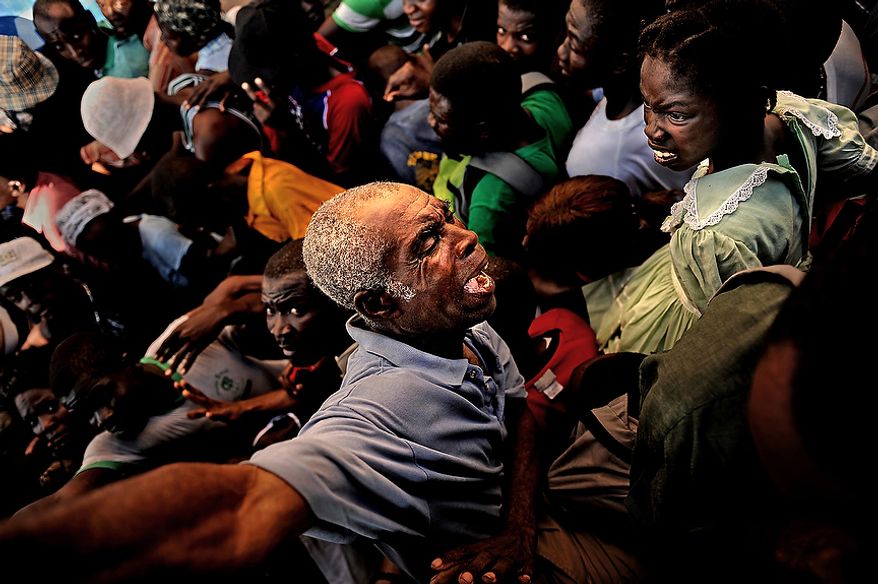 An older man is squished while he tries to get out of the way of a huge number of Haitians making their way to the relief supplies (food and water) the U.S. Army Soldiers with Charlie Company, 2nd Battalion, 325th Airborne Infantry Regiment, 2nd Brigade Combat Team, 82nd Airborne Division, Fort Bragg, NC,were handing out on January 20, 2010 at the stadium in Port au Prince, Haiti, for Operation Unified Response. As more and more Haitians heard of the distribution being handed out by the soldiers, the distribution line turned into a huge gathering of people being pushed from the back. The soldiers stood their ground and handed out the majority of the relief for as long as they could before they were hugely out numbered and over run. (U.S. Air Force photo by Tech. Sgt. Jeremy T. Lock)
