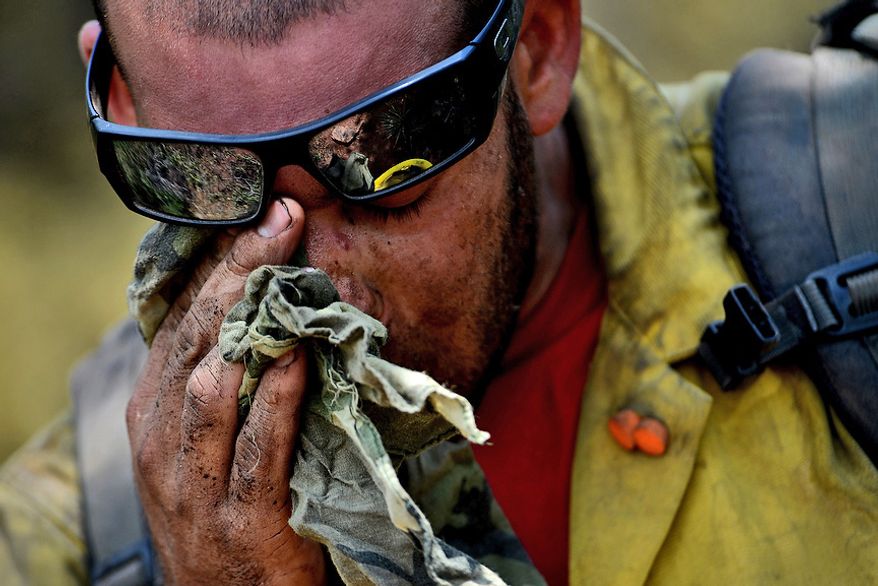 Vandenberg Air Force Base Hot Shot fire fighter Chris Loung wipes sweat from his face while cutting a fire line on June 28, 2012 in the Mount Saint Francois area of Colorado Springs, Co. while helping to battle several fires in Waldo Canyon. (U.S. Air Force photo by Tech. Sgt. Jeremy T. Lock)