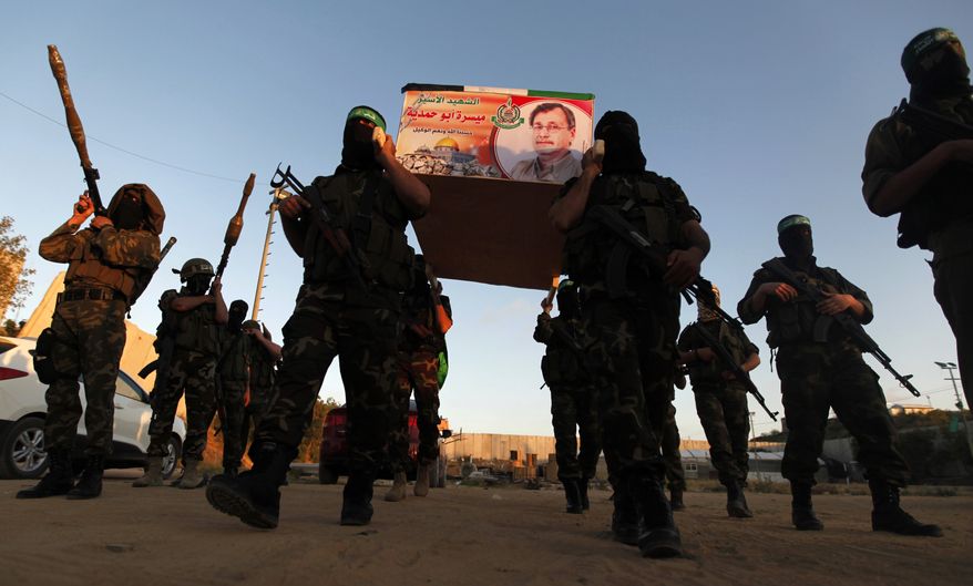 Izzedine Al-Qassam Brigades militants carry a mock coffin of Maysara Abu Hamdiyeh in the Gaza Strip on Tuesday, April 2, 2013. Abu Hamdiyeh, 64, who was serving a life sentence for his role in a foiled attempt to bomb a busy cafe in Jerusalem in 2002, died Tuesday of cancer in an Israeli jail. (AP Photo/Hatem Moussa)