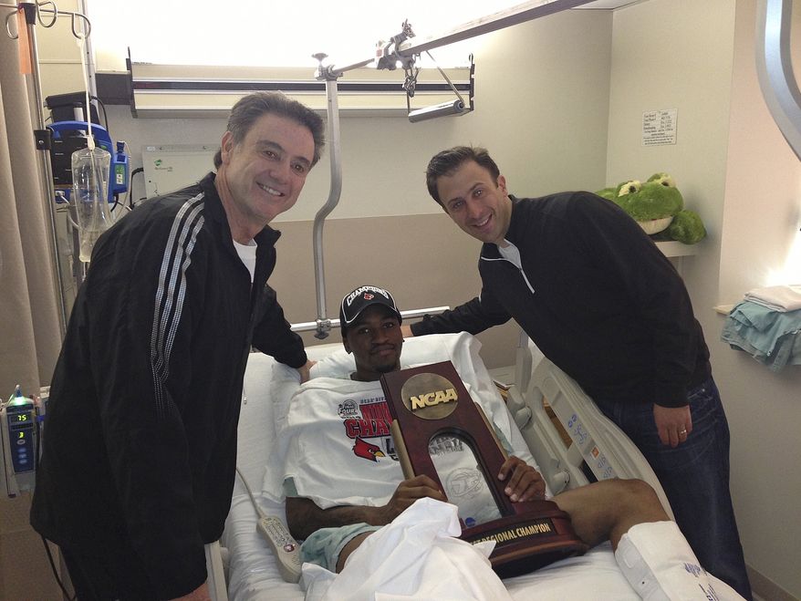 In this photo released by the University of Louisville, injured Louisville guard Kevin Ware lies in a hospital bed holding the NCAA Regional Championship trophy flanked by coach Rick Pitino, left, and former Louisville assistant coach Richard Pitino, Monday, April 1, 2013, in Louisville, Ky. Ware broke his leg in the first half of Sunday's Midwest Regional final when he landed awkwardly after trying to contest a 3-point shot, breaking his leg in two places. He was taken off the court on a stretcher as his stunned teammates openly wept. His teammates went on to defeat Duke 85-63 to reach their second straight Final Four. (AP Photo/University of Louisville, Kenny Klein)