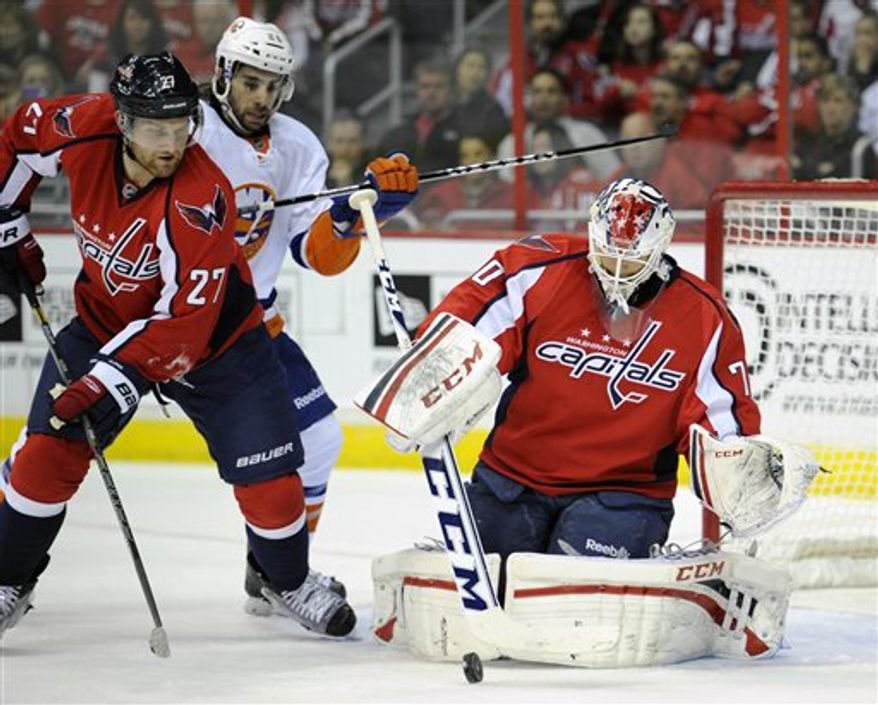 Washington Capitals goalie Braden Holtby (70) stops the puck against New York Islanders left wing Matt Moulson, center, during the second period of an NHL hockey game on Thursday, April 4, 2013, in Washington. Capitals defenseman Karl Alzner (27) looks on. (AP Photo/Nick Wass)