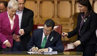 Connecticut Gov. Dannel P. Malloy (center) signs legislation at the Capitol in Hartford, Conn., on Thursday, April 4, 2013, to place new restrictions on weapons and large-capacity ammunition magazines, a response to last year&#39;s deadly school shooting in Newtown, Conn. Neil Heslin (behind left), father of Sandy Hook shooting victim Jesse Lewis; Nicole Hockley (right), mother of Sandy Hook School shooting victim Dylan Hockley; and Lt. Gov. Nancy Wyman (left) look on. (AP Photo/Steven Senne)