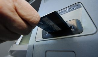 A person demonstrates using a credit card in an ATM machine in Pittsburgh on Jan. 5, 2013. (Associated Press)