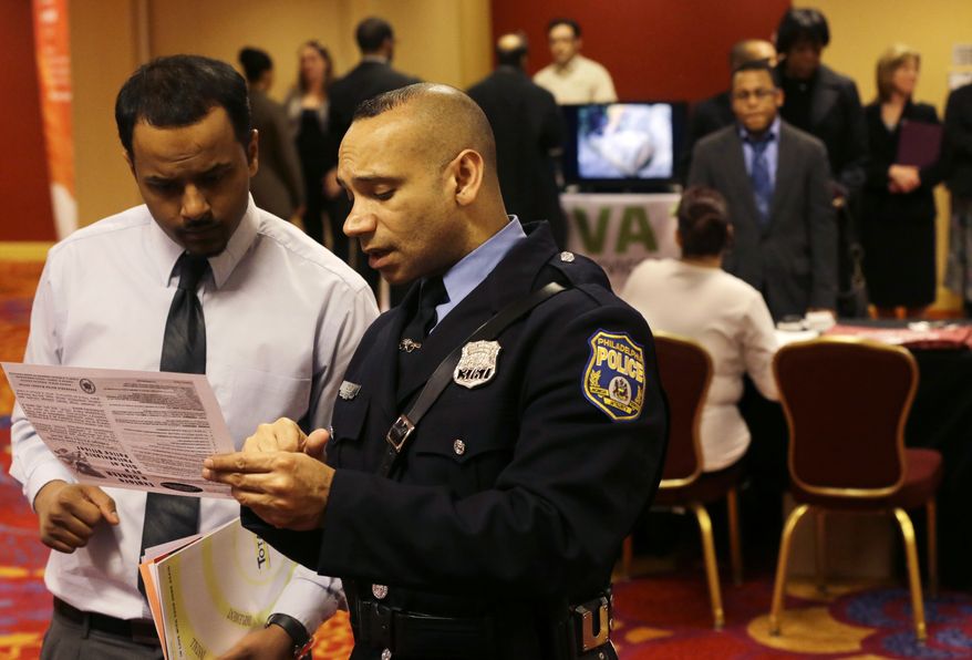 Officer Samuel Cruz (right), a Philadelphia police recruiter, talks with Ismail Azeer of Carteret, N.J., at the Edison Career Fair in the Iselin section of Woodbridge Township, N.J., on Tuesday, Feb. 26, 2013. (AP Photo/Mel Evans)