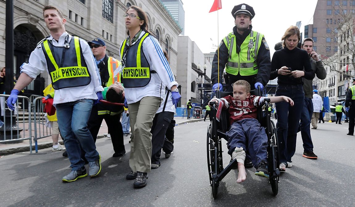 A Boston police officer wheels in injured boy down Boylston Street as medical workers carry an injured runner following an explosion during the 2013 Boston Marathon in Boston, Monday, April 15, 2013. Two explosions shattered the euphoria at the marathon&#x27;s finish line on Monday, sending authorities out on the course to carry off the injured while the stragglers were rerouted away from the smoking site of the blasts. (AP Photo/Charles Krupa)
