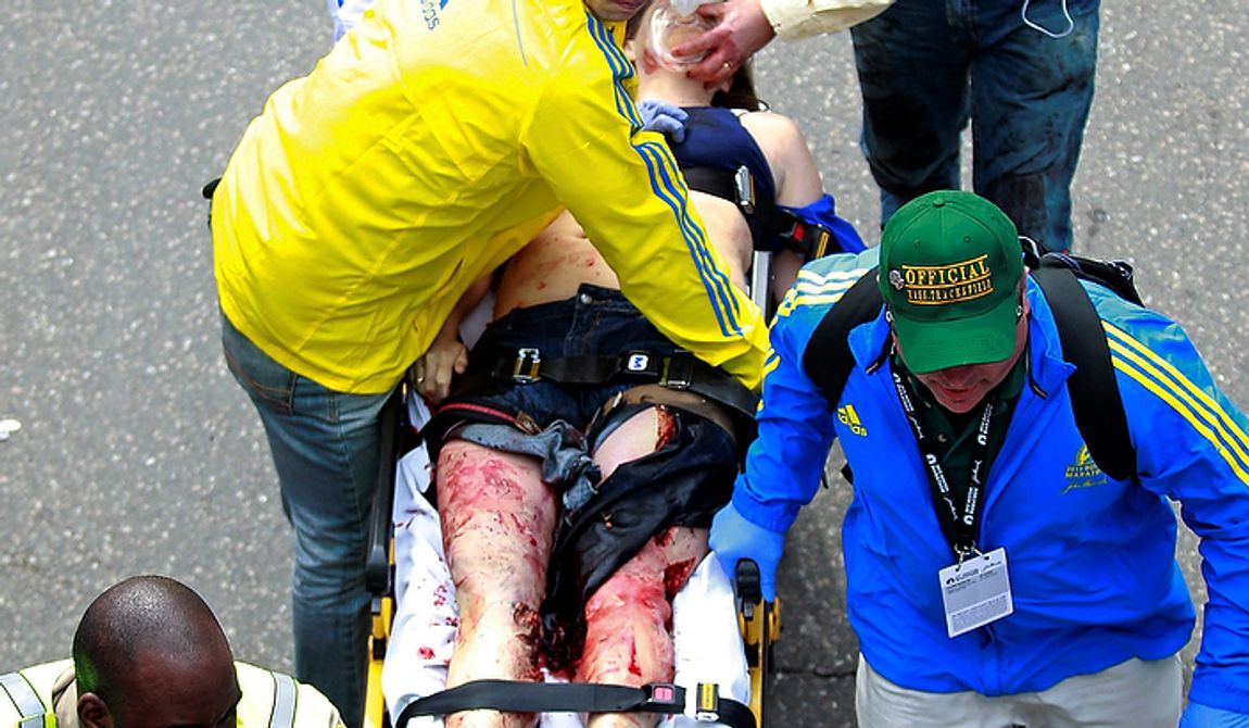 Medical workers aid an injured man at the finish line of the 2013 Boston Marathon following an explosion in Boston, Monday, April 15, 2013. Two bombs exploded near the finish of the Boston Marathon on Monday, killing two people, injuring 22 others and sending authorities rushing to aid wounded spectators, race organizers and police said. (AP Photo/Charles Krupa)