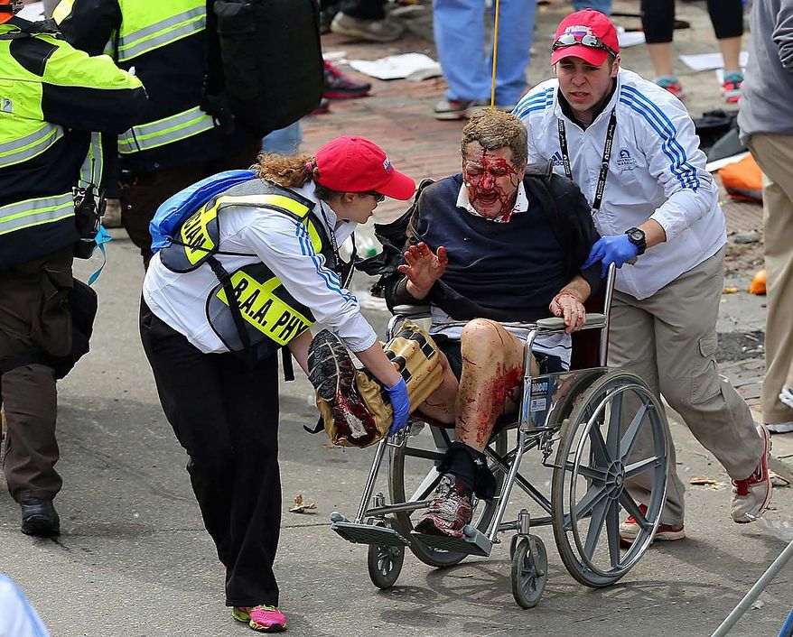 Medical workers aid an injured man at the 2013 Boston Marathon following an explosion in Boston, Monday, April 15, 2013. Two bombs exploded near the finish of the Boston Marathon on Monday, killing at least two people, injuring at least 22 others and sending authorities rushing to aid wounded spectators. (AP Photo/The Boston Globe, David L. Ryan)