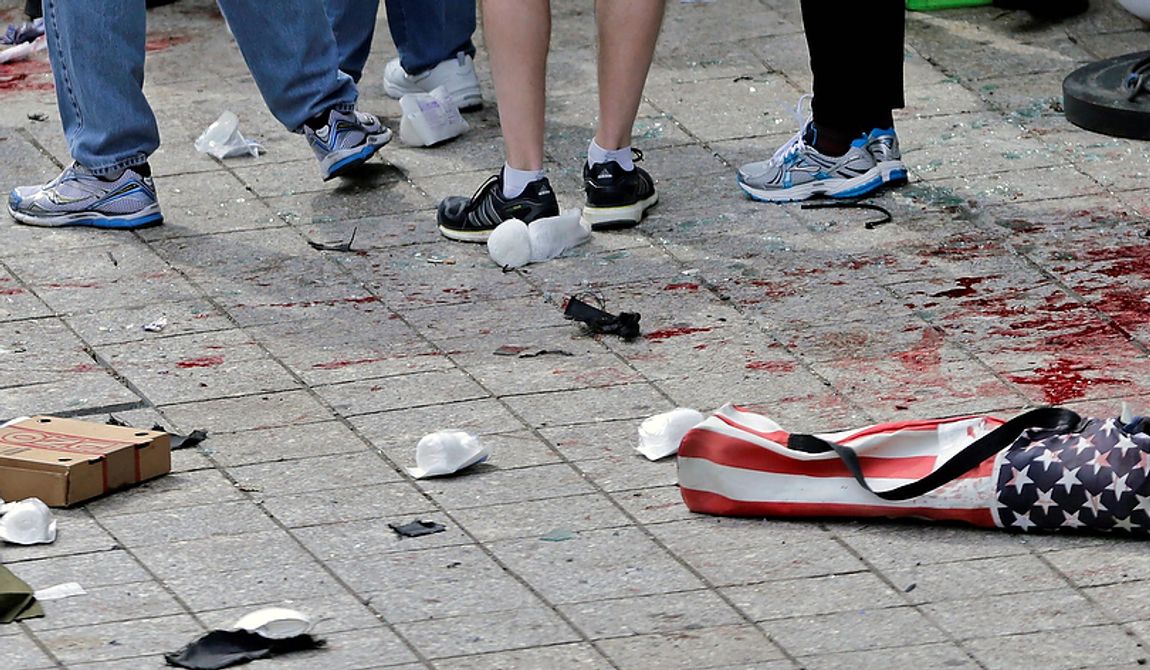 Blood from victims covers the sidewalk on Boylston Street, at the site of an explosion during the 2013 Boston Marathon in Boston, Monday, April 15, 2013. At the right foreground is a folding chair with the design of an American flag on the cover.  Two explosions shattered the euphoria of the Boston Marathon finish line on Monday, sending authorities out on the course to carry off the injured while the stragglers were rerouted away from the smoking site of the blasts. (AP Photo/Charles Krupa)