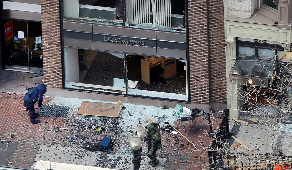 ** FILE ** One of the blast sites on Boylston Street near the finish line of the 2013 Boston Marathon is investigated by two people in protective suits in the wake of two blasts in Boston Monday, April 15, 2013. (AP Photo/Elise Amendola)