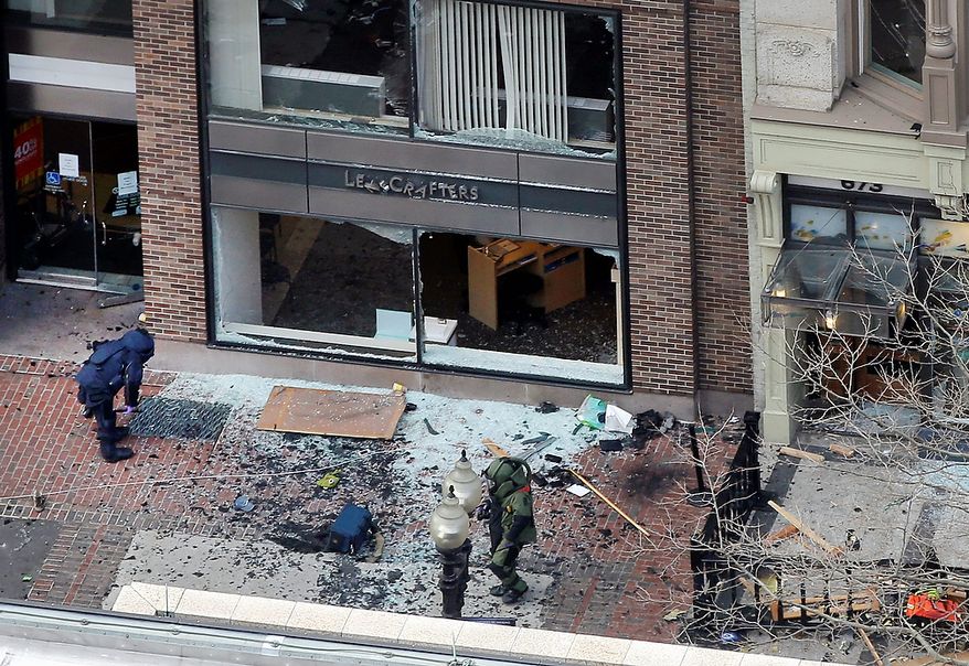 ** FILE ** One of the blast sites on Boylston Street near the finish line of the 2013 Boston Marathon is investigated by two people in protective suits in the wake of two blasts in Boston Monday, April 15, 2013. (AP Photo/Elise Amendola)