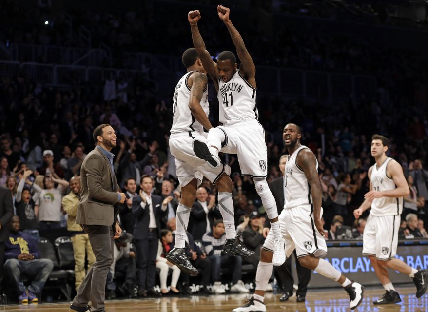 Brooklyn Nets Deron Williams, left, in street clothes, watches as teammates Tyshawn Taylor (41) and MarShon Brooks (9) celebrate after Taylor hit a three-point shot in the Nets 106-101 victory over the Washington Wizards in an NBA basketball game, Monday, April 15, 2013, in New York. Andray Blatche, who was the Nets high scorer, reacts, second from right. (AP Photo/Kathy Willens)