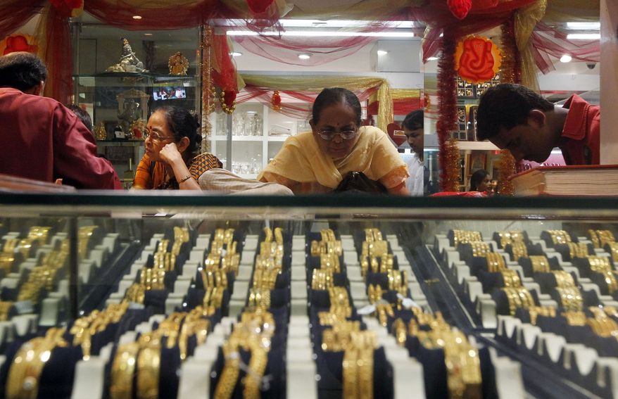 An Indian woman looks at a display of gold jewelry at a shop in Mumbai on Thursday, Feb. 14, 2013. The price of gold has plunged, suggesting that a decade-long surge in the precious metal is over. (AP Photo/Rajanish Kakade)