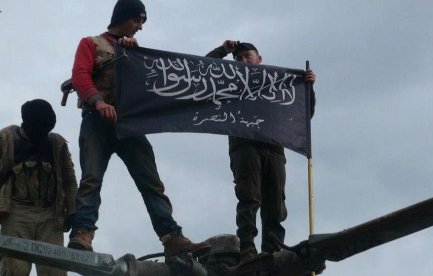 ** FILE ** Rebels from al-Qaeda-affiliated Jabhat al-Nusra wave their brigade flag as they step atop a Syrian air force helicopter at the Taftanaz Air Base, which was was captured by the rebels, on Friday, Jan. 11, 2013, in Idlib province in northern Syria. (AP Photo/Edlib News Network)